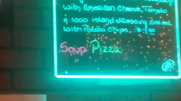 A neon sign declaring the soup of the day to be Pizza