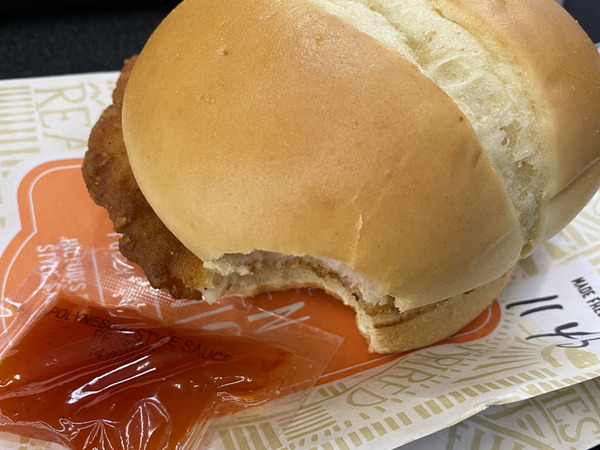 A chicken sandwich with a sauce packet