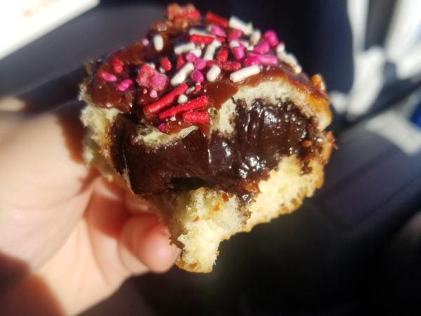 A partially-eaten donut with chocolate frosting and chocolate filling.