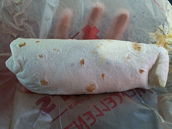 The burrito. It looks hefty. A creepy hand is looming behind the wrapper holding it.